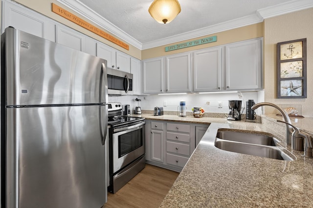 1700 Scenic Highway 98 Unit 101, Destin, FL 32541 - kitchen with stainless steel appliances, ornamental molding, wood finished floors, light stone countertops, and decorative backsplash