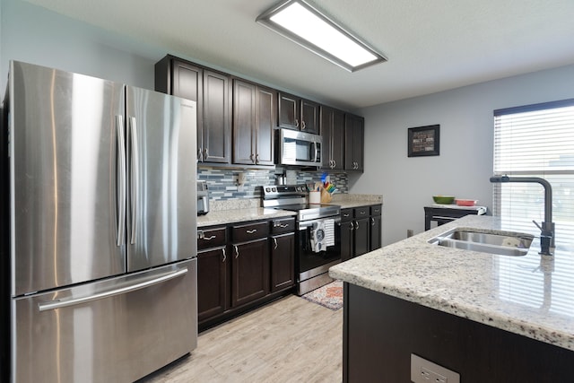 4605 Plover Dr, Crestview, FL 32539 - kitchen featuring appliances with stainless steel finishes, decorative backsplash, light wood-style floors, light stone countertops, and dark brown cabinetry
