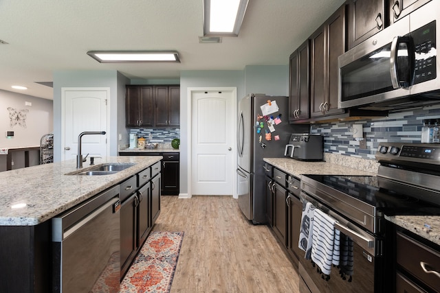 4605 Plover Dr, Crestview, FL 32539 - kitchen featuring appliances with stainless steel finishes, tasteful backsplash, light stone counters, light wood-type flooring, and dark brown cabinetry