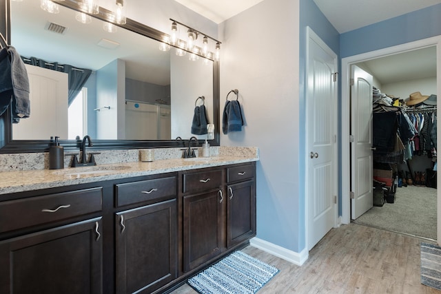 4605 Plover Dr, Crestview, FL 32539 - bathroom featuring double vanity, wood finished floors, a spacious closet, and a shower