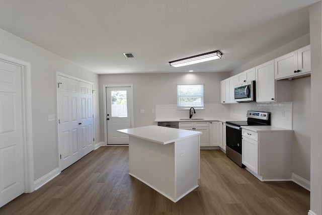 5360 Highview Dr, Crestview, FL 32539 - kitchen featuring stainless steel appliances, wood finished floors, backsplash, white cabinetry, and light countertops