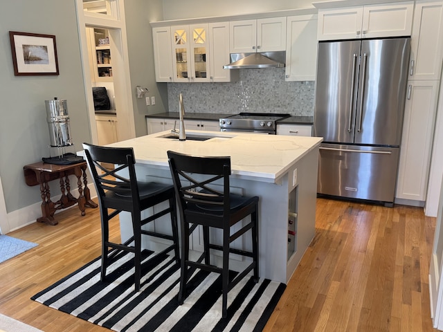 209 Dune Crest Ln, Panama City Beach, FL 32413 - kitchen with appliances with stainless steel finishes, ventilation hood, light wood-type flooring, white cabinets, and decorative backsplash