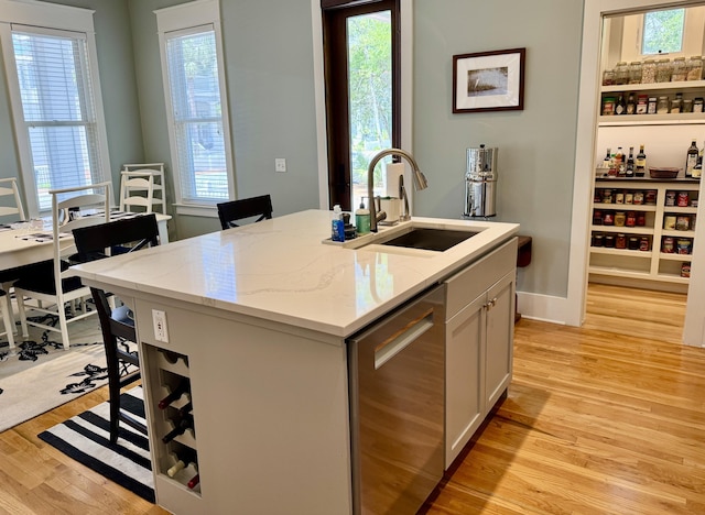 209 Dune Crest Ln, Panama City Beach, FL 32413 - kitchen with dishwasher, light wood-type flooring, light stone countertops, a kitchen island with sink, and white cabinets