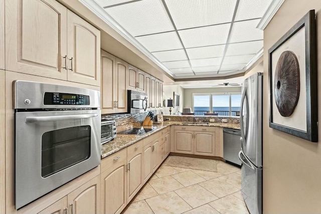 6323 Thomas Dr Unit 904B, Panama City Beach, FL 32408 - kitchen featuring appliances with stainless steel finishes, light brown cabinets, light stone counters, backsplash, and a ceiling fan