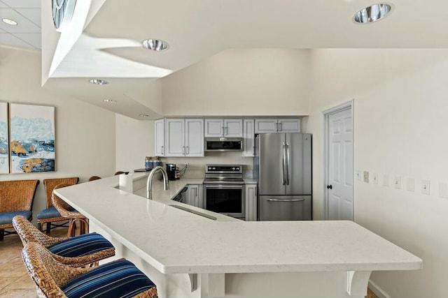 6323 Thomas Dr Unit 904B, Panama City Beach, FL 32408 - kitchen with stainless steel appliances, a peninsula, a kitchen bar, recessed lighting, and lofted ceiling