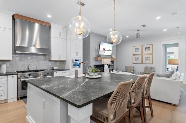 4564 Nautical Ct, Destin, FL 32541 - kitchen with open floor plan, stainless steel appliances, light wood-style floors, wall chimney range hood, and tasteful backsplash