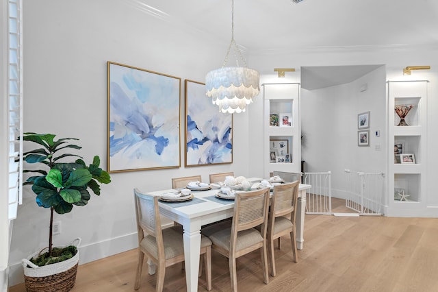 4564 Nautical Ct, Destin, FL 32541 - dining space with light wood-type flooring, ornamental molding, built in shelves, and a chandelier