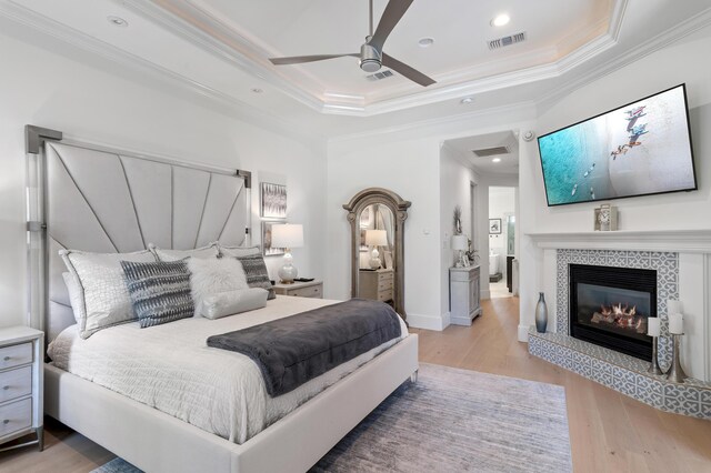 4564 Nautical Ct, Destin, FL 32541 - bedroom featuring crown molding, wood finished floors, a tray ceiling, a tile fireplace, and a ceiling fan