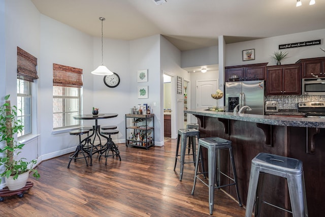 222 Raptor Dr, Crestview, FL 32536 - kitchen featuring appliances with stainless steel finishes, a kitchen breakfast bar, dark brown cabinetry, dark wood-style floors, and decorative backsplash