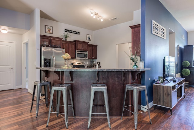 222 Raptor Dr, Crestview, FL 32536 - kitchen featuring stainless steel appliances, dark wood-type flooring, a breakfast bar, dark brown cabinets, and decorative backsplash