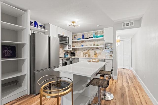 210 Pelham Rd Unit 211B, Fort Walton Beach, FL 32547 - kitchen featuring open shelves, appliances with stainless steel finishes, a kitchen bar, decorative backsplash, and light countertops