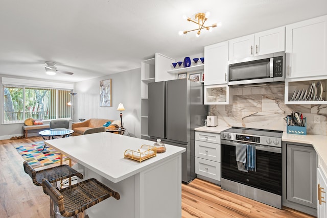 210 Pelham Rd Unit 211B, Fort Walton Beach, FL 32547 - kitchen featuring appliances with stainless steel finishes, light countertops, tasteful backsplash, a breakfast bar, and light wood-style floors