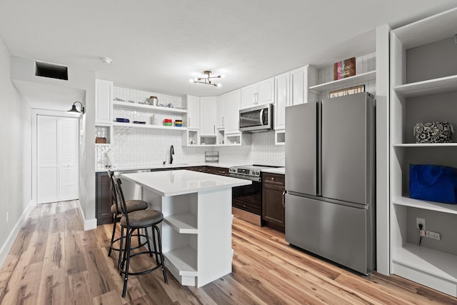 210 Pelham Rd Unit 210B, Fort Walton Beach, FL 32547 - kitchen featuring stainless steel appliances, open shelves, decorative backsplash, light countertops, and a kitchen breakfast bar