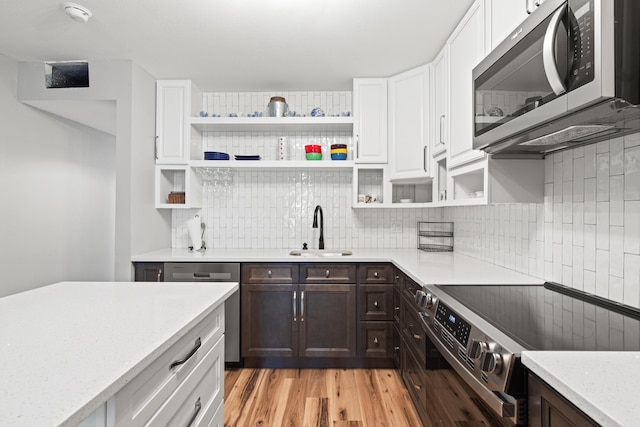 210 Pelham Rd Unit 210B, Fort Walton Beach, FL 32547 - kitchen with appliances with stainless steel finishes, open shelves, white cabinetry, dark brown cabinets, and tasteful backsplash