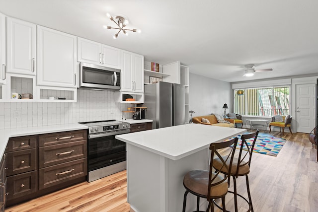 210 Pelham Rd Unit 210B, Fort Walton Beach, FL 32547 - kitchen featuring stainless steel appliances, open shelves, white cabinets, a breakfast bar area, and light countertops