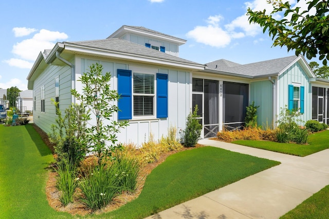 8450 Dreams Float Ct, Panama City Beach, FL 32413 - view of front of house featuring board and batten siding, a sunroom, and a front yard