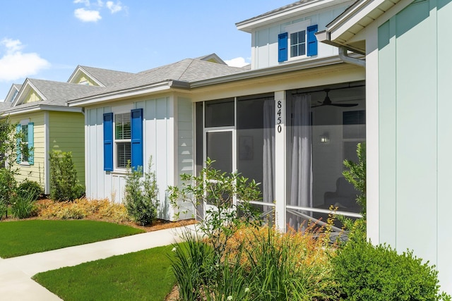 8450 Dreams Float Ct, Panama City Beach, FL 32413 - view of property exterior with board and batten siding, a sunroom, roof with shingles, and a lawn