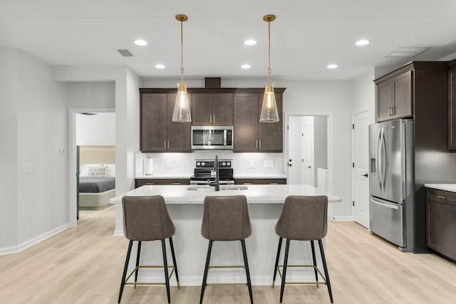 8450 Dreams Float Ct, Panama City Beach, FL 32413 - kitchen featuring appliances with stainless steel finishes, light wood finished floors, dark brown cabinets, and recessed lighting