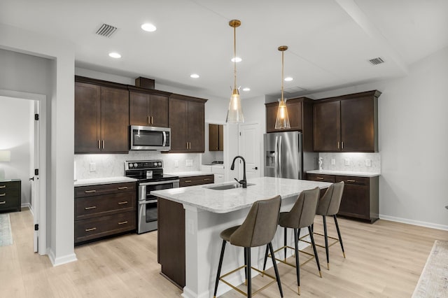 8450 Dreams Float Ct, Panama City Beach, FL 32413 - kitchen with appliances with stainless steel finishes, backsplash, dark brown cabinetry, light wood-type flooring, and recessed lighting