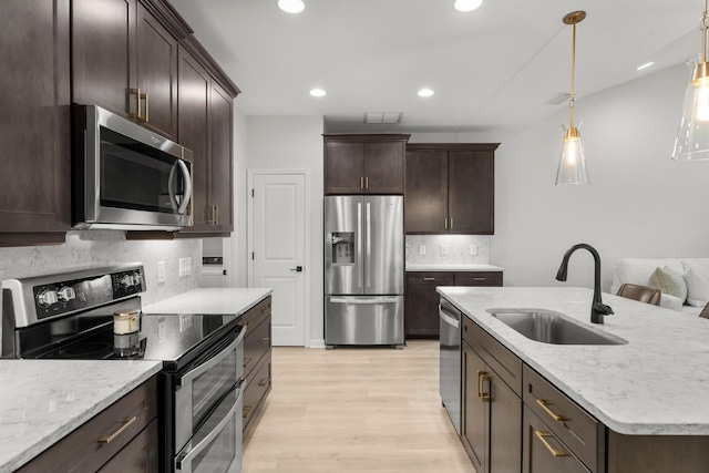 8450 Dreams Float Ct, Panama City Beach, FL 32413 - kitchen featuring stainless steel appliances, light wood-style floors, decorative backsplash, dark brown cabinetry, and recessed lighting