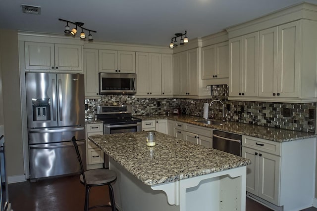 574 Avalon Blvd, Miramar Beach, FL 32550 - kitchen featuring stainless steel appliances, decorative backsplash, light stone counters, and a center island