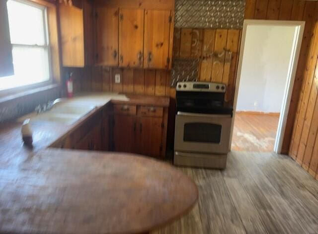 2032 Brogdon St, Grand Ridge, FL 32442 - kitchen featuring electric stove, brown cabinetry, light wood-style flooring, wood walls, and light countertops