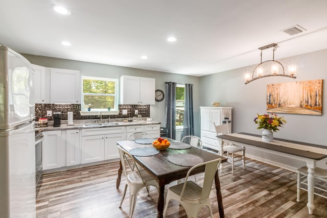 2141 C Shelby Ln, Westville, FL 32464 - kitchen featuring freestanding refrigerator, light wood finished floors, tasteful backsplash, white cabinets, and light countertops