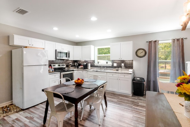 2141 C Shelby Ln, Westville, FL 32464 - kitchen with stainless steel appliances, light wood-style flooring, white cabinetry, backsplash, and recessed lighting