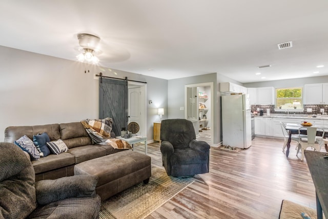 2141 C Shelby Ln, Westville, FL 32464 - living room featuring a barn door, light wood finished floors, and a ceiling fan