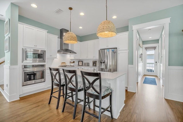 654 Flatwoods Forest Loop, Santa Rosa Beach, FL 32459 - kitchen with appliances with stainless steel finishes, light wood finished floors, wall chimney exhaust hood, a center island, and a wainscoted wall