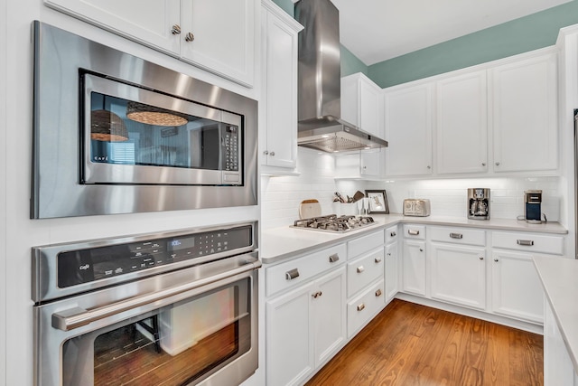 654 Flatwoods Forest Loop, Santa Rosa Beach, FL 32459 - kitchen featuring stainless steel appliances, wall chimney exhaust hood, light countertops, white cabinets, and backsplash