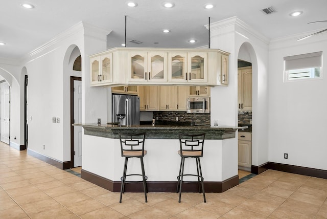3929 Indian Springs Rd, Panama City, FL 32404 - kitchen featuring cream cabinets, backsplash, a kitchen bar, dark countertops, and ornamental molding