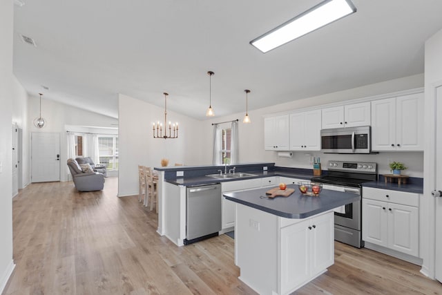 277 Limestone Cir, Crestview, FL 32539 - kitchen with dark countertops, stainless steel appliances, white cabinetry, vaulted ceiling, and a peninsula