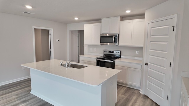 4408 Marine Loop, Crestview, FL 32539 - kitchen featuring range with electric stovetop, stainless steel microwave, light wood-style floors, a kitchen island with sink, and white cabinetry