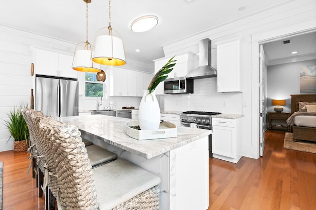 12 Seabreeze Way, Inlet Beach, FL 32461 - kitchen featuring wall chimney exhaust hood, backsplash, a kitchen bar, appliances with stainless steel finishes, and wood finished floors