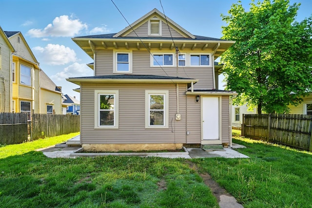 rear view of house with a fenced backyard and a yard