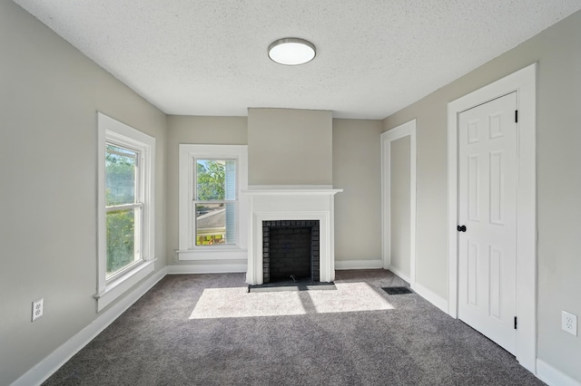 unfurnished living room featuring carpet floors, a textured ceiling, a fireplace with flush hearth, and baseboards