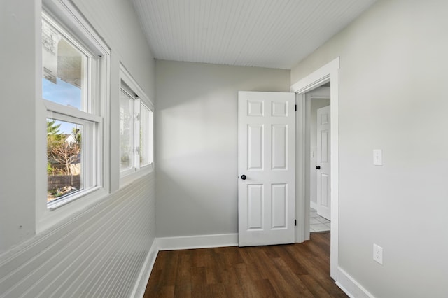 hall featuring baseboards and dark wood-type flooring