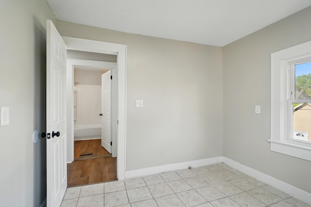 empty room with baseboards, visible vents, and light tile patterned floors