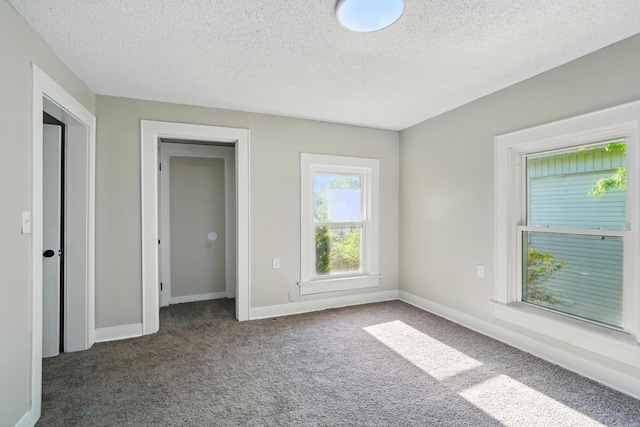 unfurnished bedroom with carpet flooring, a textured ceiling, and baseboards