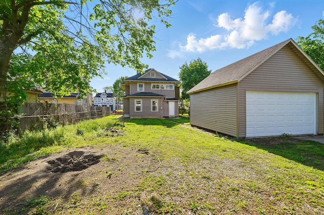 view of yard with a detached garage, fence, and an outbuilding