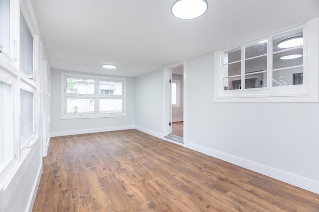 unfurnished living room featuring baseboards, wood finished floors, and a healthy amount of sunlight