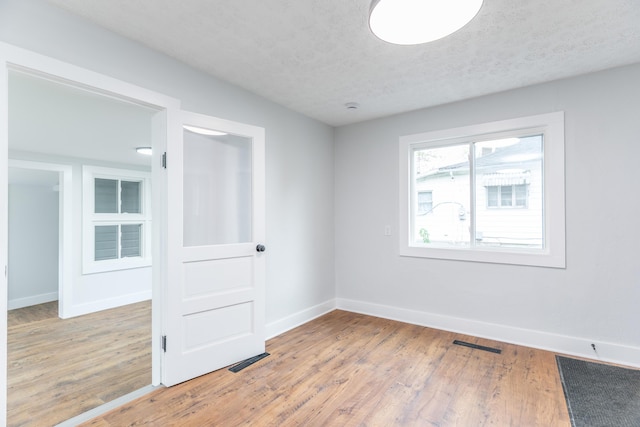 unfurnished room featuring visible vents, wood finished floors, and baseboards