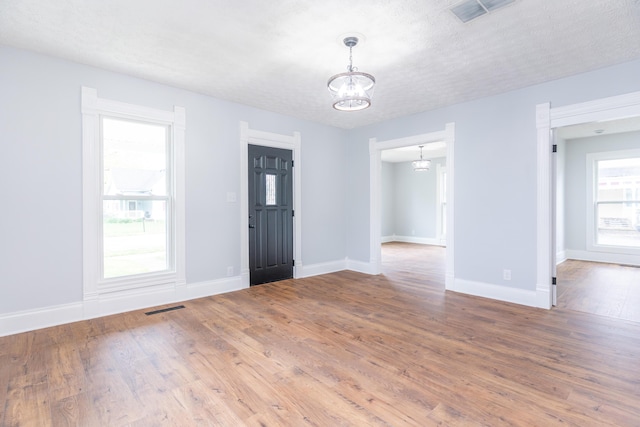 entrance foyer with an inviting chandelier, wood finished floors, visible vents, and baseboards