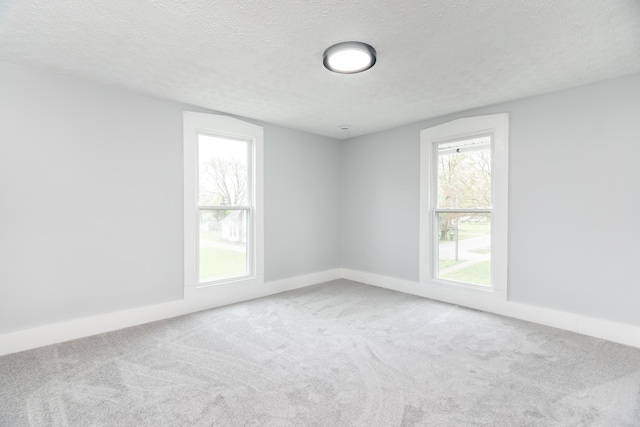 carpeted spare room with baseboards and a textured ceiling