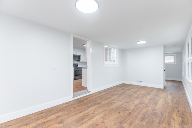 basement with wood finished floors, visible vents, and baseboards