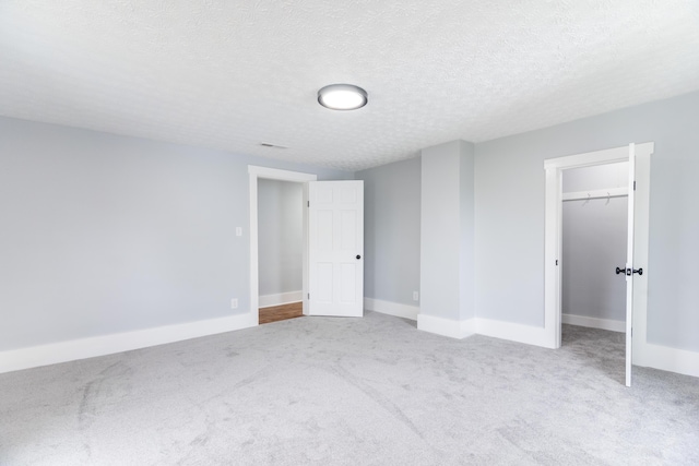 unfurnished bedroom with a closet, carpet flooring, a textured ceiling, and baseboards