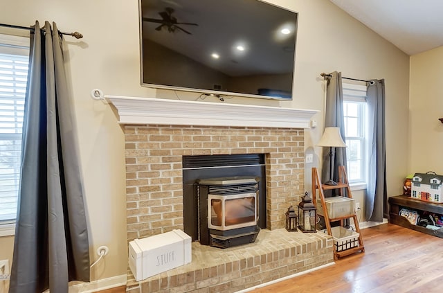 room details featuring a wood stove, ceiling fan, and wood-type flooring