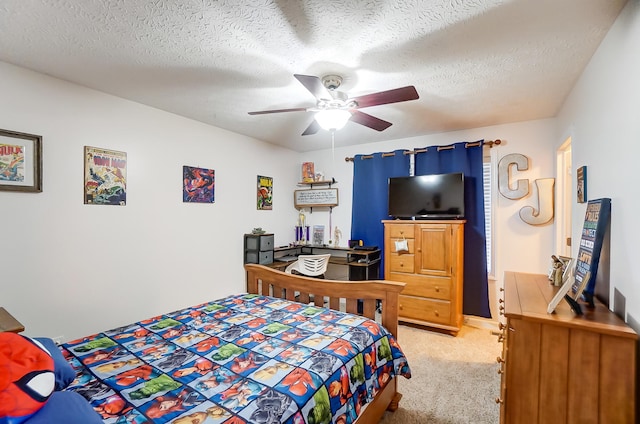 bedroom featuring a textured ceiling, light colored carpet, and ceiling fan