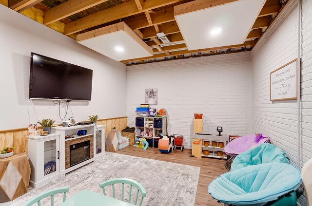 rec room with hardwood / wood-style flooring and brick wall